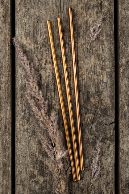 Free photo stainless metallic golden straws on wooden background