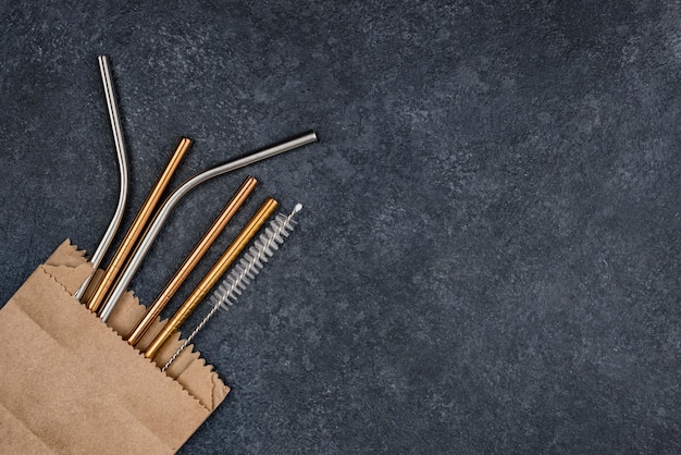 Stainless metallic straws in a paper bag copy space