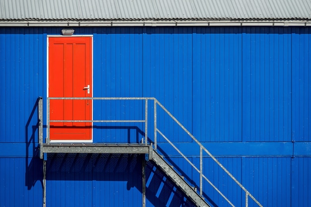 Staircase near the blue wall of a garage leading to the red door