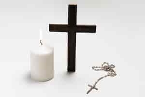 Free photo standing cross with lit candle and necklace