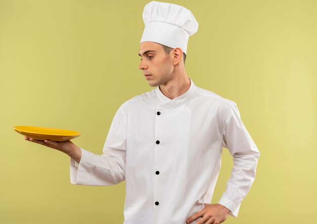 프로필보기 젊은 남성 요리사 입고 요리사 유니폼을 입고 서있는 그의 손에 접시를 찾고 복사 공간 엉덩이에 손을 넣어