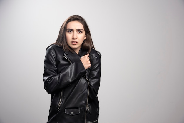 Standing woman freezes in leather jacket warms up by hugging herself