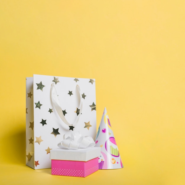 Star shape shopping bag; paper hat and gift box on yellow background