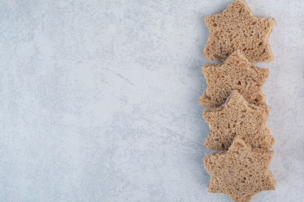 Free photo star shaped black bread slices on stone surface