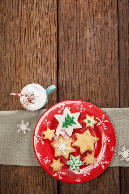 Звезда печенье в форме на красной тарелке и чашки со сливками