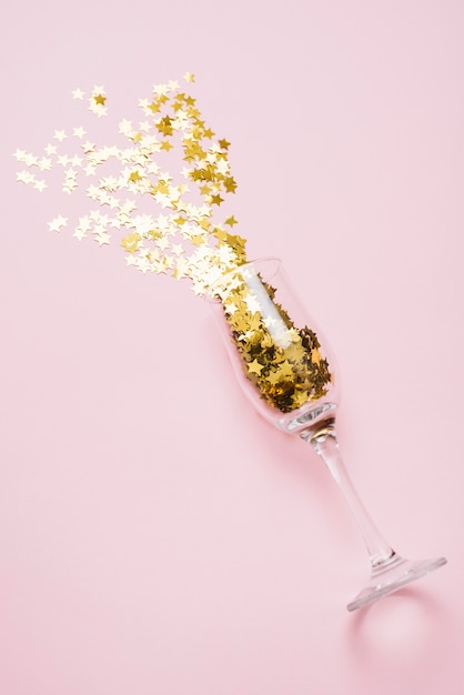 Star spangles scattered from glass on pink table