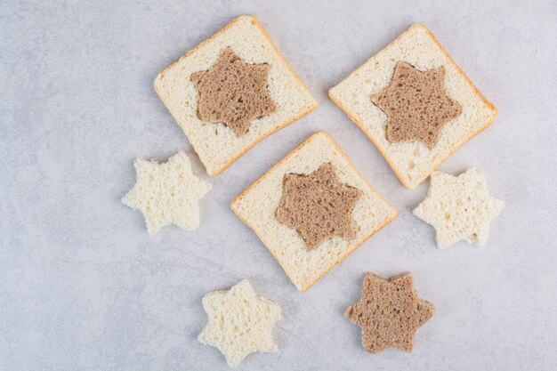 Star and square shaped black and white bread slices on stone surface