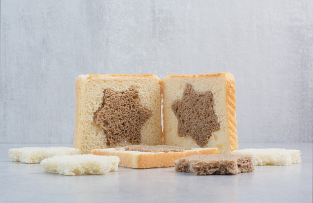 Star and square shaped black and white bread slices on stone table