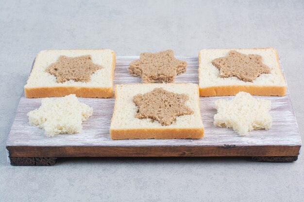 Ломтики черного и белого хлеба в форме звезды и квадрата на деревянной тарелке