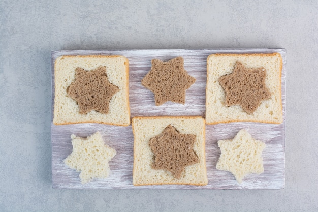 Star and square shaped black and white bread slices on wooden plate