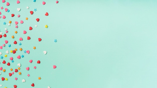 Бесплатное фото Звезды и сердца конфетти на бирюзовом фоне с копией пространства