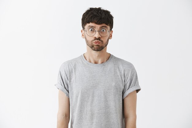 Startled handsome guy posing against the white wall