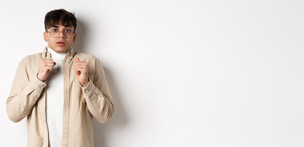 Free photo startled man freeze from fear gasping and looking scared at camera standing in glasses on white back