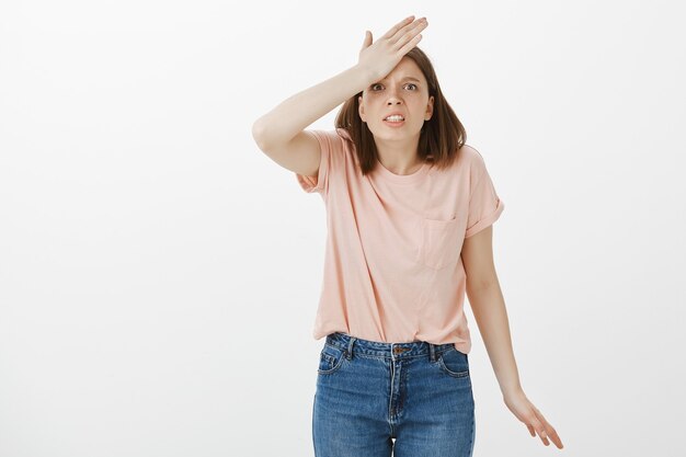 Startled woman remember something, punch forehead and looking worried