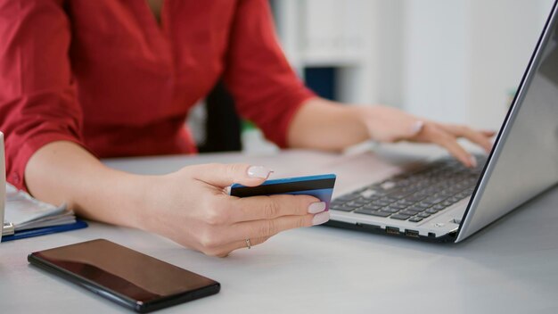 Startup employee doing online shopping with credit card on laptop, using banking money to purchase on sale. Office employee making transaction for e commerce development. Close up.