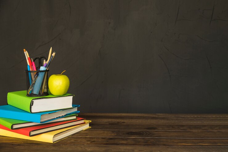Free Photo stationary and apple on pile of books at table