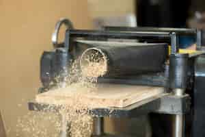 Free photo stationary power woodworking planer processing wooden flooring board, making sawdust
