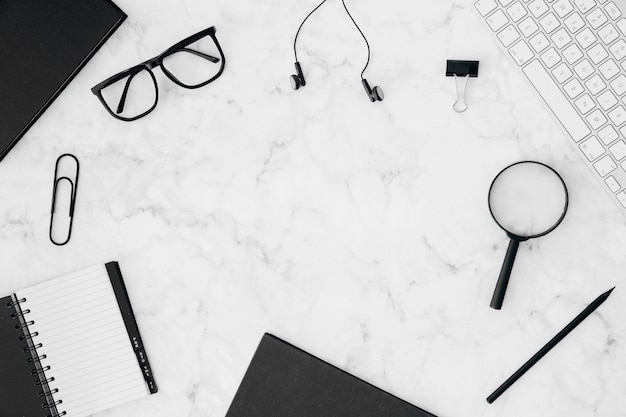 Stationeries; keyboard and eyeglasses on white marble textured background