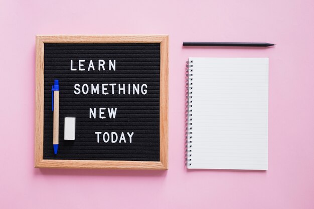 Stationeries with learn something new today text on slate over pink backdrop