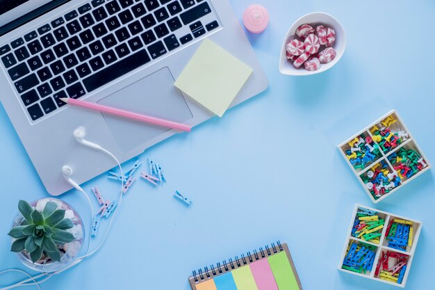 Stationery and candies near laptop and earphones