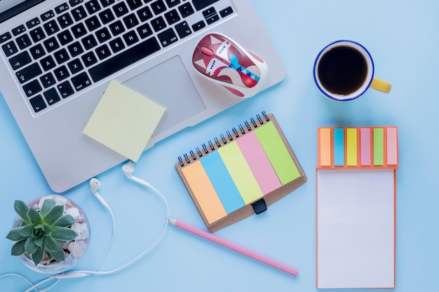 Stationery and coffee near laptop and earphones