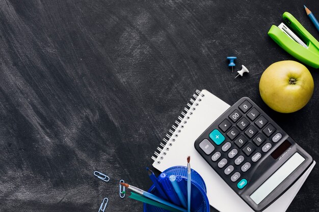 Stationery with apple and calculator on blackboard