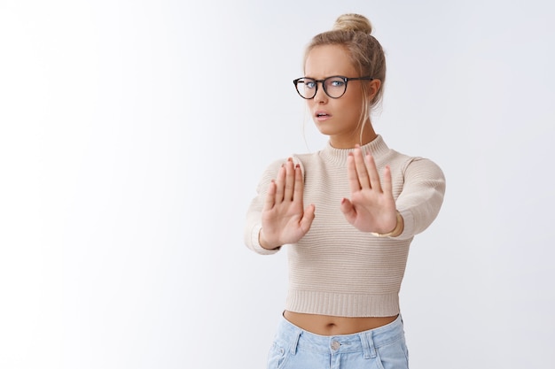 Foto gratuita stammi lontano. ritratto di un'intensa donna europea dispiaciuta dall'aspetto serio che spinge fuori lo sconosciuto che è troppo rumoroso che mostra i palmi delle mani in stop e nessun gesto, rifiutando un'offerta disgustosa