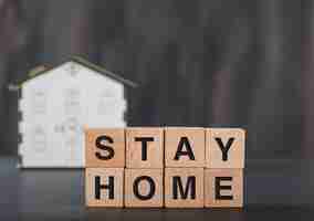 Free photo stay home concept with wooden cubes, house model grey.