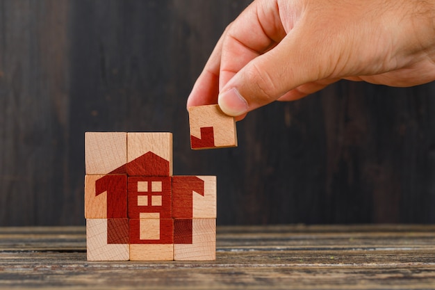 Stay at home concept on wooden table side view. hand holding wooden cube.