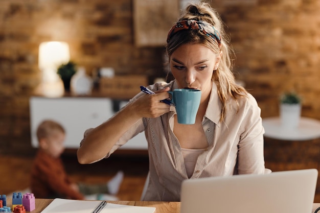 Stay at home mother drinking coffee while working on a computer