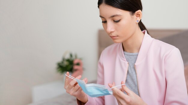 医療マスクを保持している女性の屋内に滞在