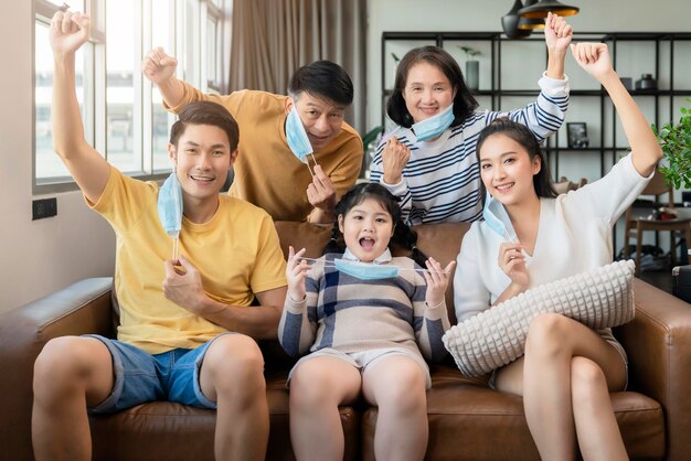 Stay strong healthy asian family multi generation wearing virus protective face mask stay quarantane together at living room home background social distacing new normal lifestyle