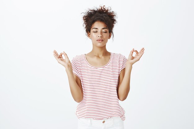 Staying calm and relaxed woman with afro hairstyle posing in the studio