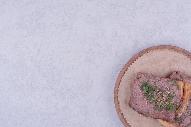 Steak meat slices with herbs and spices on a wooden board.