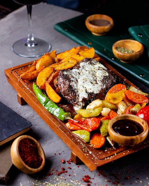 Steak served with potatoes grilled vegetable salad and sauce