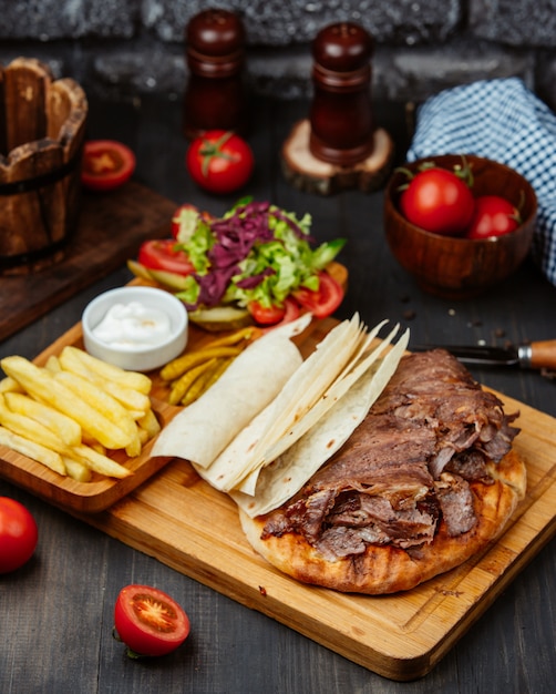 steak slices on top of pita bread, fries, fresh salad and mayo