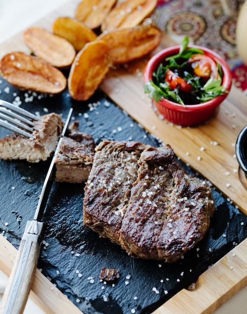 Steak with vegetable salad and fried potatoes.