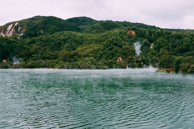 Steam coming out of a beautiful body of water surrounded by green mountains