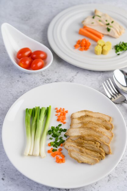 ネギとにんじんのみじん切りの白い皿に鶏の胸肉を蒸し