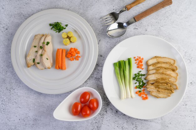 ネギとにんじんのみじん切りの白い皿に鶏の胸肉を蒸し