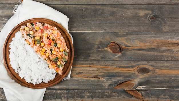 Steamed rice and fried rice on wooden plate over the white napkin on wooden table