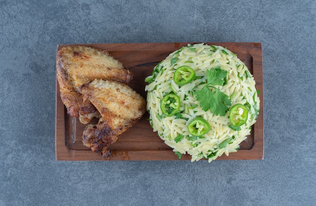 Riso al vapore con parti di pollo su tavola di legno.