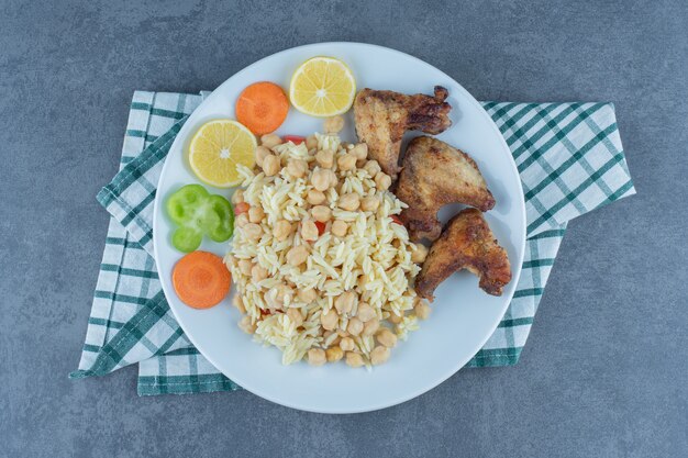 白い皿にひよこ豆と手羽先を添えたご飯。