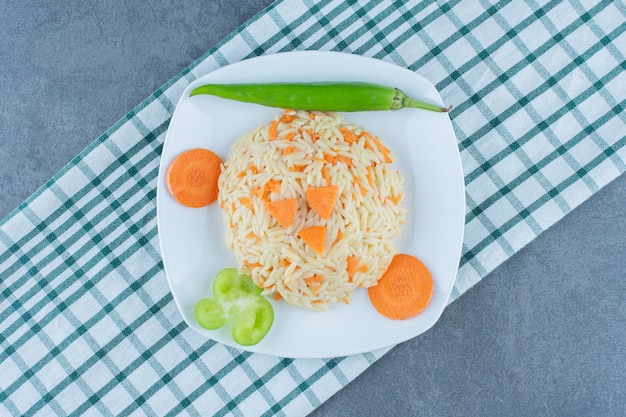 Вареный рис с нарезанной морковью на белой тарелке.