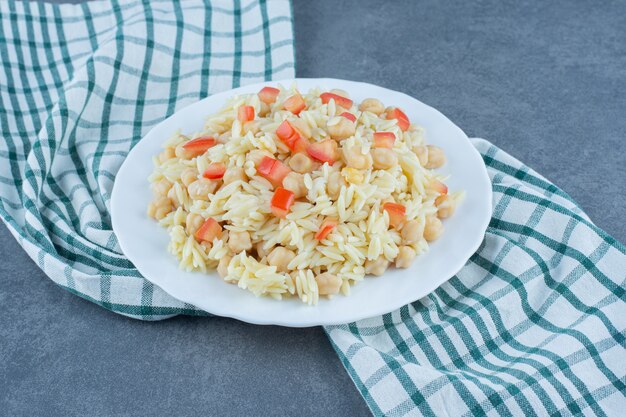 Steamed rice with peas and tomato slices on white plate. 