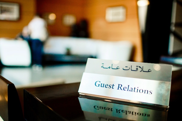 Free photo steel card with lettering 'guest relations' stands on the table