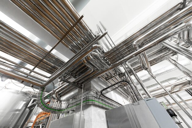 Steel pipelines and cables in factory interior as nuclear industry background concept