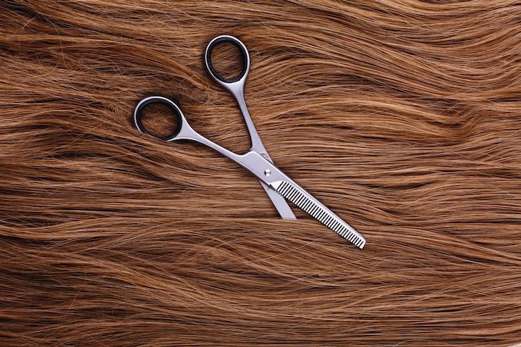 Free Photo steel scissors lie on the wave of silk brown hair