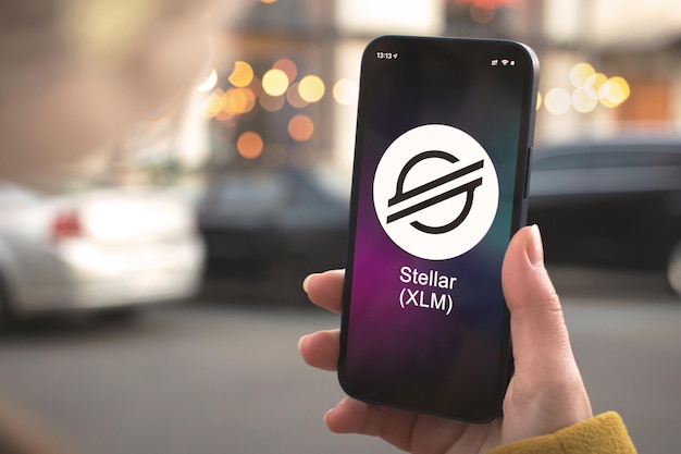 Stellar xlm cryptocurrency symbol, logo. business and financial concept. hand with smartphone, screen with crypto icon close-up