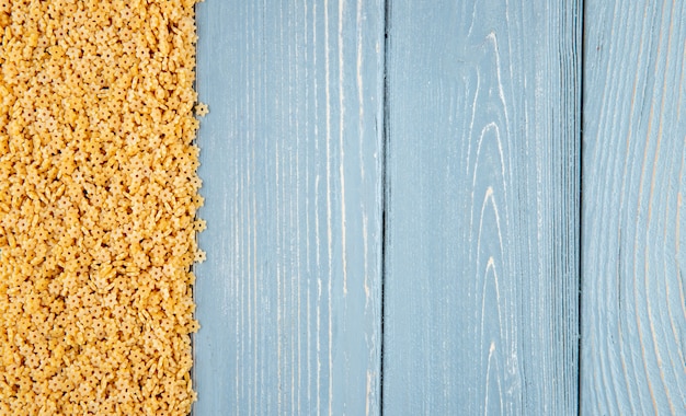 Stelline pasta on the blue wooden background copy space